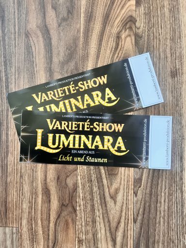 Zwei Tickets für die Varieté-Show "Luminara" auf schwarzem Hintergrund.