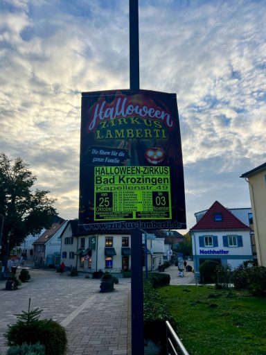Das Plakat kündigt eine Halloween-Veranstaltung in einem Stadtzentrum an.